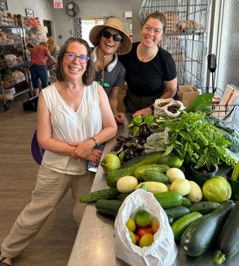 Three woman with their harvested produce.